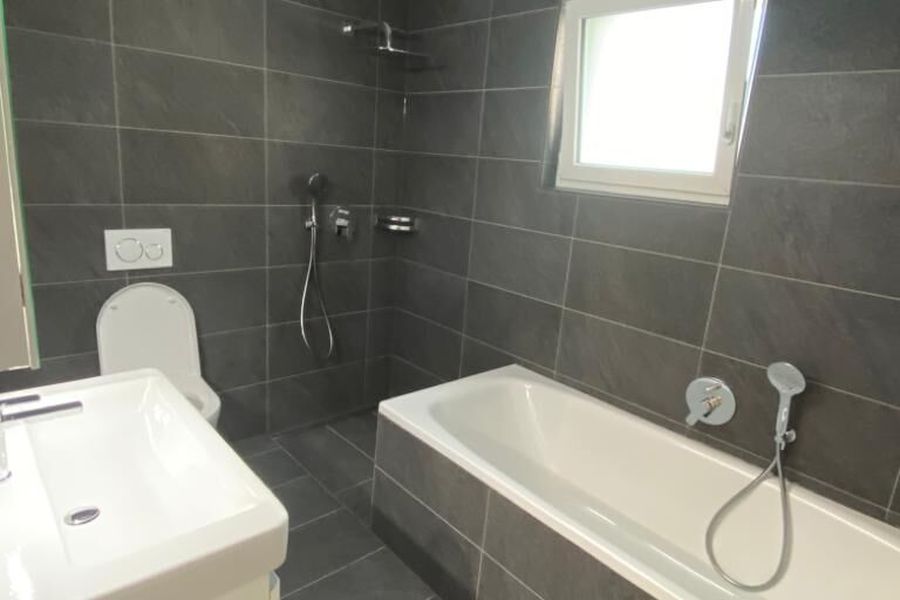 Badezimmer mit dunklen Wand- und Bodenplatten