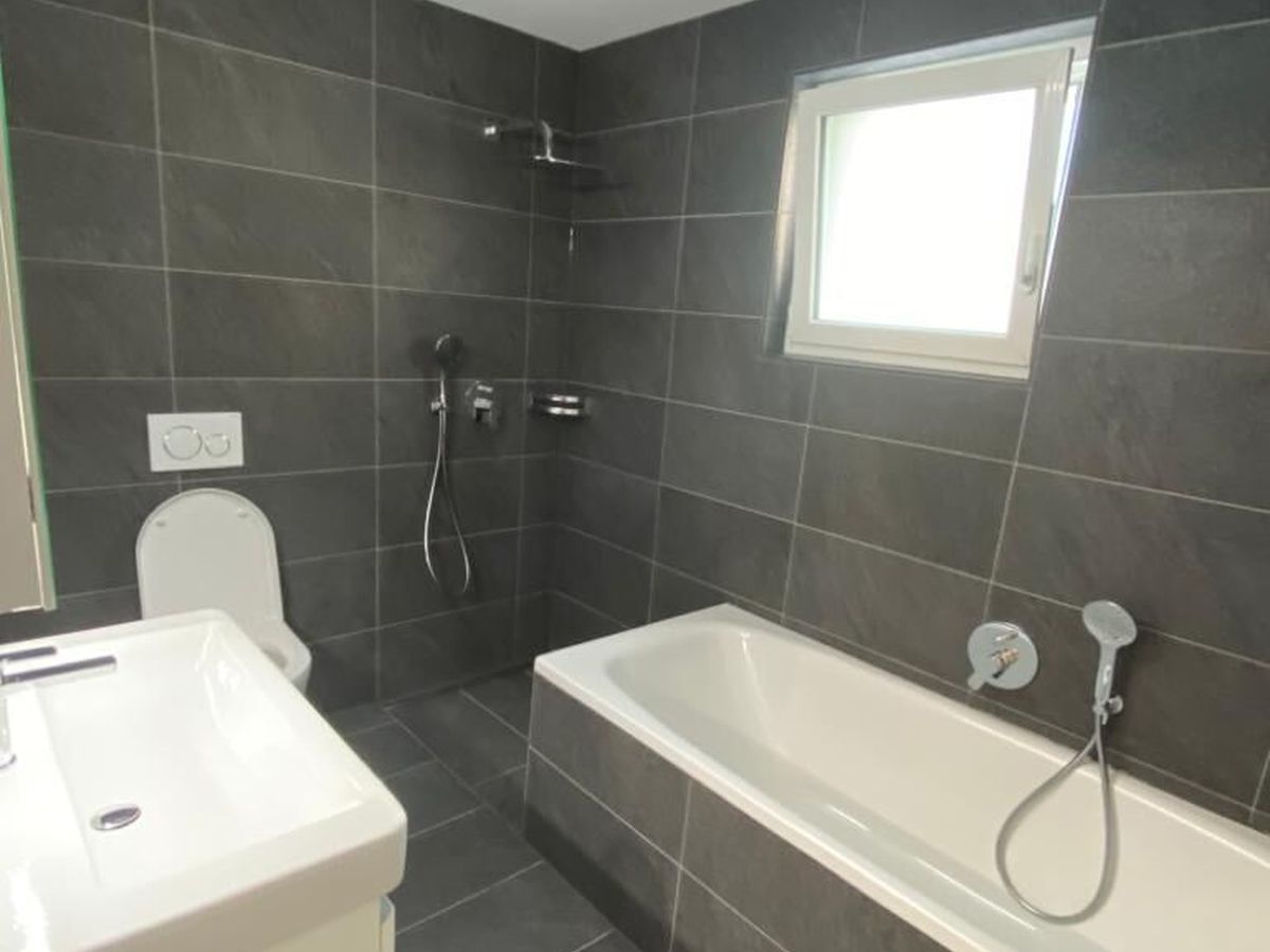 Badezimmer mit dunklen Grossformatplatten an Wand und Boden