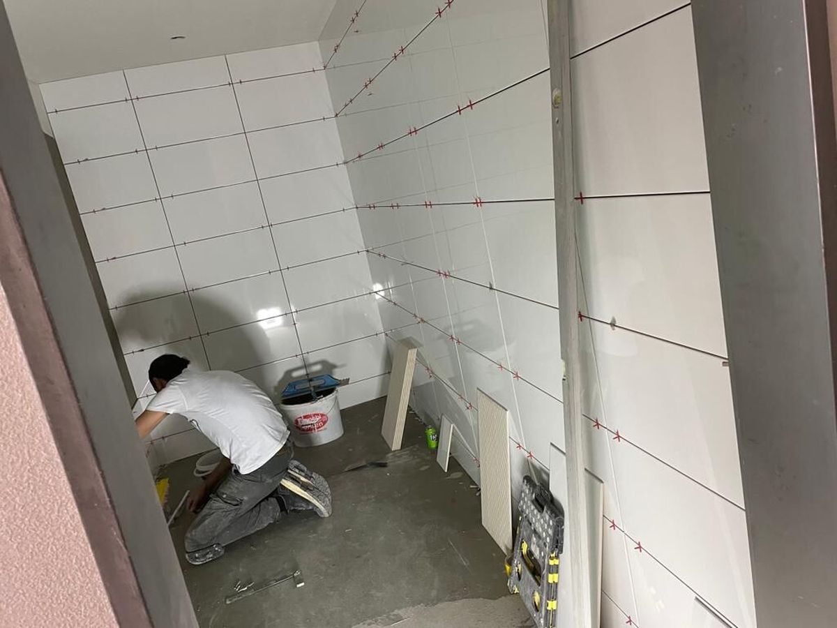 Mitarbeiter verlegt Wandplatten in einem Bad